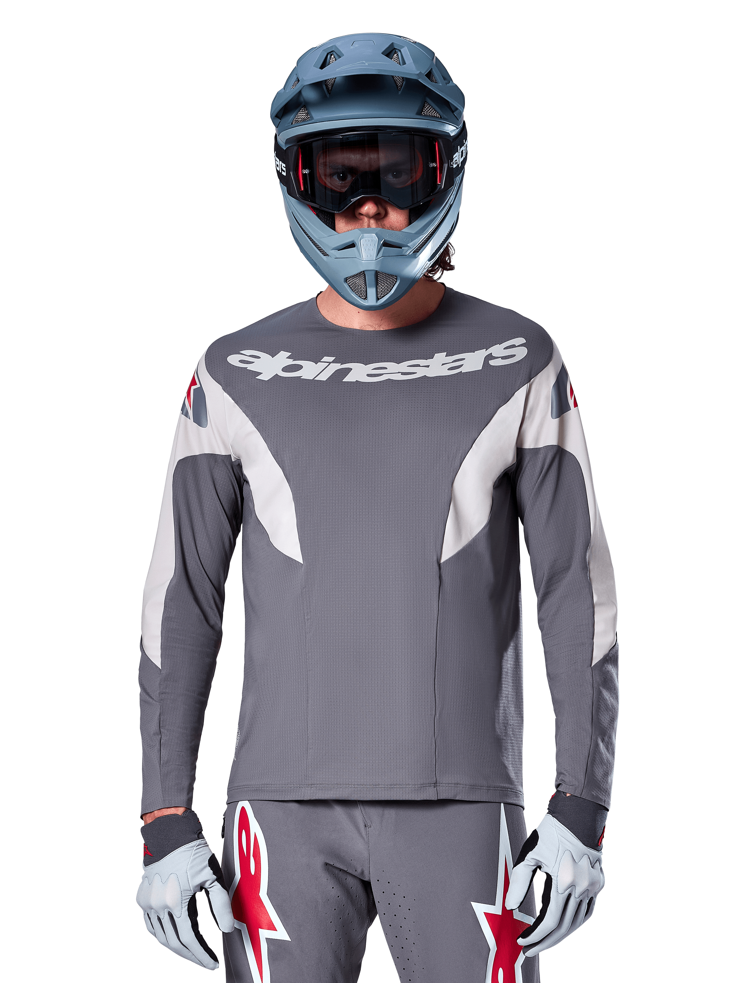 Pilote de VTT portant le maillot Alpinestars A-Supra Race - Manches longues en gris foncé, maillot de cyclisme à manches longues avec logo Alpinestars blanc, associé à un casque intégral gris-bleu, un masque et des gants de course gris, équipement de VTT complet pour la performance tout-terrain