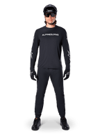 Maillot à manches longues Alpinestars A-Dura Switch, noir, porté par un cycliste de VTT avec pantalon et casque noirs assortis, arborant un logo textuel blanc sur la poitrine, vêtement technique de cyclisme tout-terrain