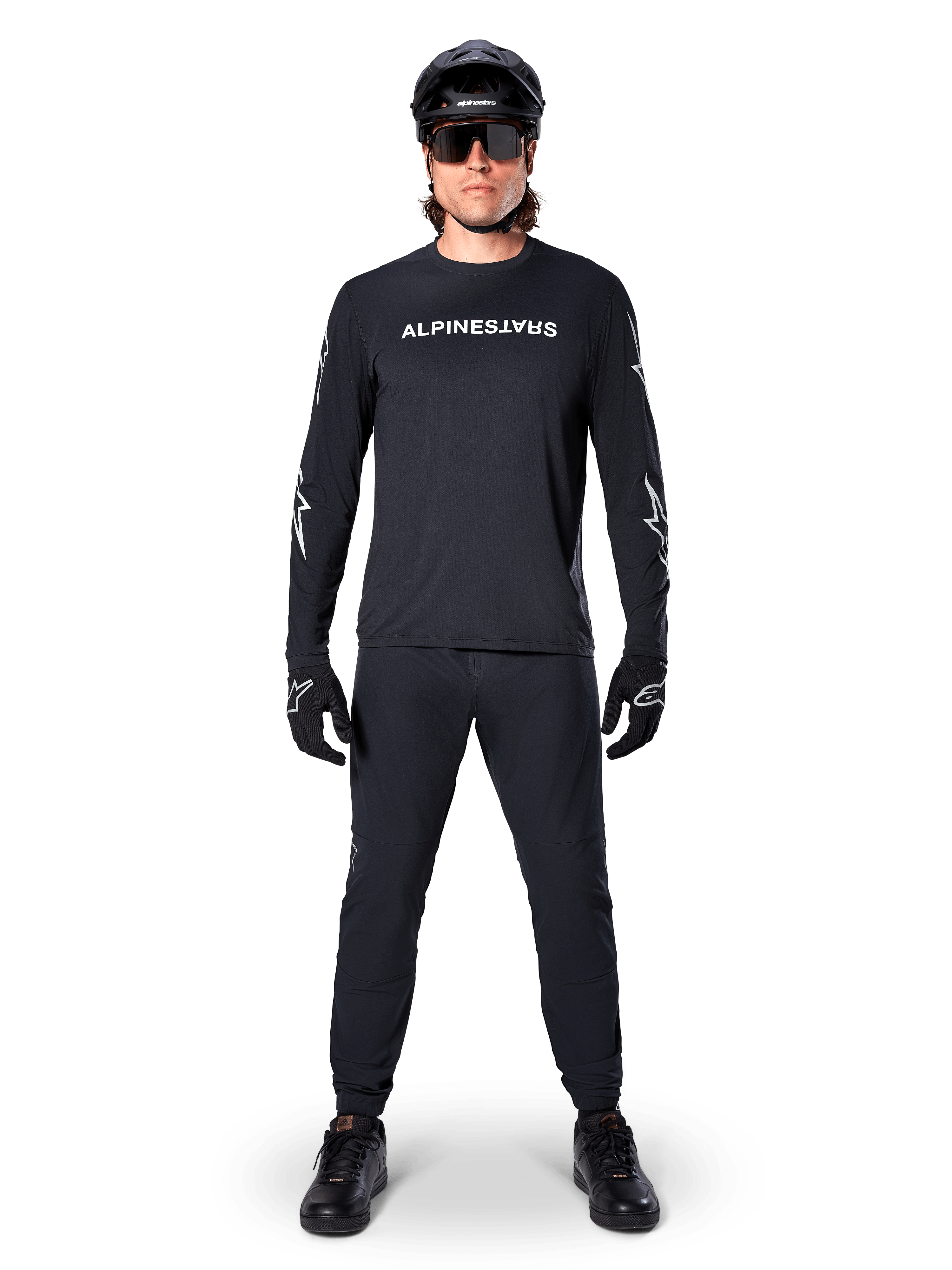 Maillot à manches longues Alpinestars A-Dura Switch, noir, porté par un cycliste de VTT avec pantalon et casque noirs assortis, arborant un logo textuel blanc sur la poitrine, vêtement technique de cyclisme tout-terrain
