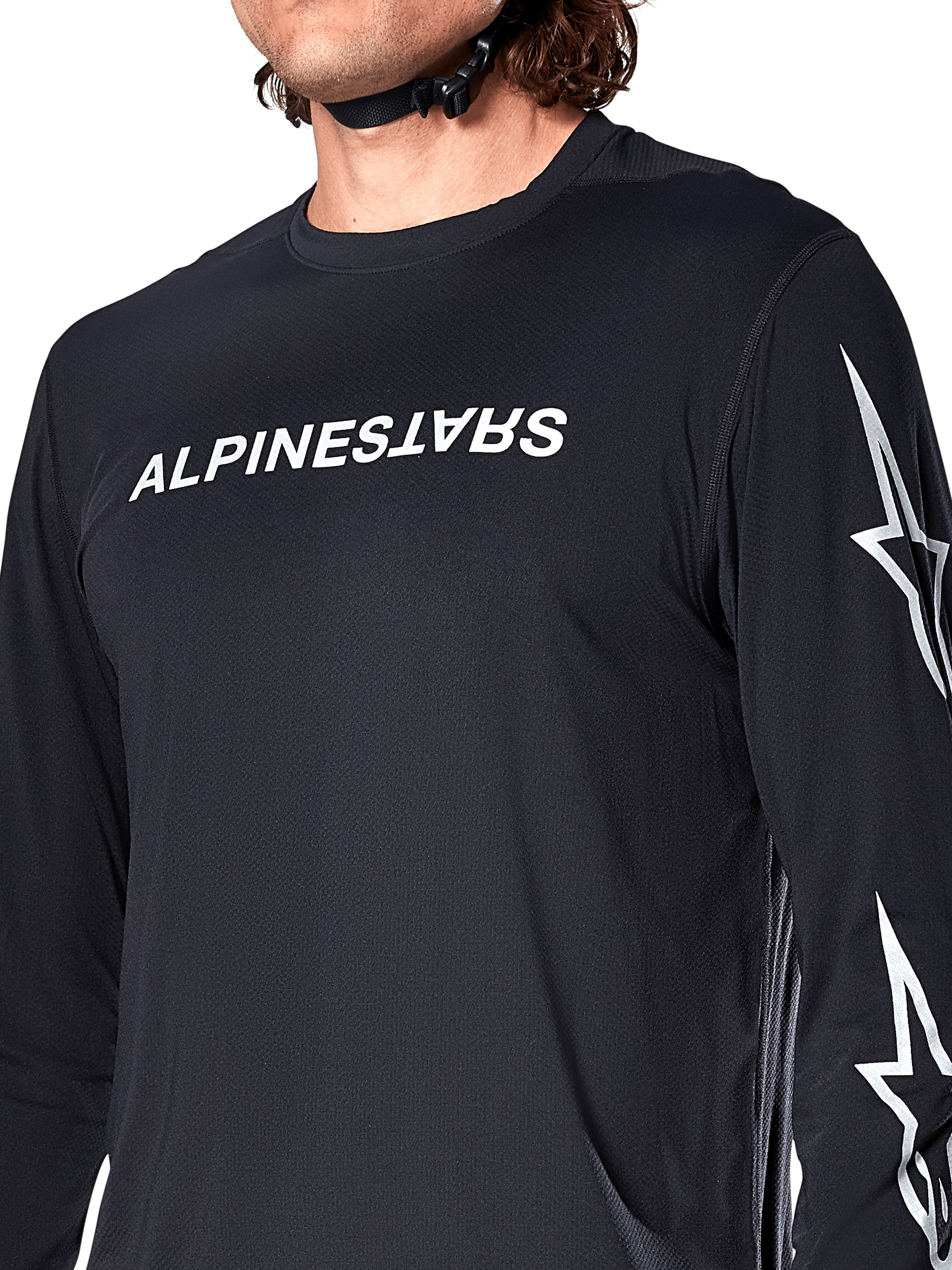 Maillot à manches longues Alpinestars A-Dura Switch, noir, avec logo Alpinestars blanc sur la poitrine et logos étoiles sur la manche, porté par un cycliste avec une sangle de casque visible, vêtement technique de VTT