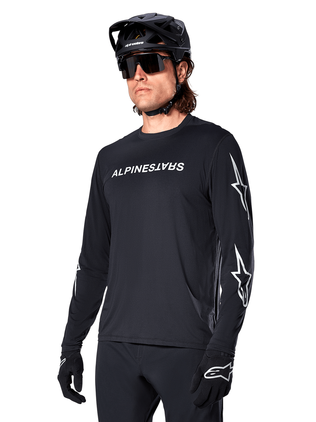 Cycliste masculin portant le maillot à manches longues Alpinestars A-Dura Switch, noir avec marquage blanc et logos étoiles sur les manches, avec casque de VTT noir et lunettes de soleil, équipement de cyclisme haute performance pour le tout-terrain