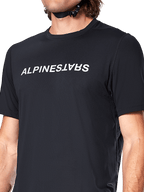 Alpinestars A-Dura Switch Jersey met korte mouwen, zwart, voorzien van een groot wit gezeefdrukt woordmerklogo op de borst, technische jacquardstof textuur, close-up vooraanzicht