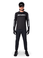 Alpinestars A-Dura Dri Oscar Long Sleeve Jersey in Black Reflective, worn with a black helmet and sunglasses, featuring white chest logo and reflective graphic patterns on the sleeves, MTB gear for off-road riding