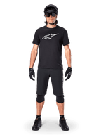 Alpinestars A-Dura Dri Oscar Kurzarmtrikot, Schwarz reflektierend, getragen mit passenden schwarzen MTB-Shorts, Handschuhen, Knieschützern und Helm, mit großem weißem Alpinestars-Logo auf der Brust, komplettes Mountainbike-Outfit