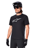 Alpinestars A-Dura Dri Oscar Trikot, Kurzarm-MTB-Radtrikot, Schwarz mit weißem Logo, feuchtigkeitsableitendes Funktionsmaterial, getragen mit schwarzem Helm, Sonnenbrille und Handschuhen