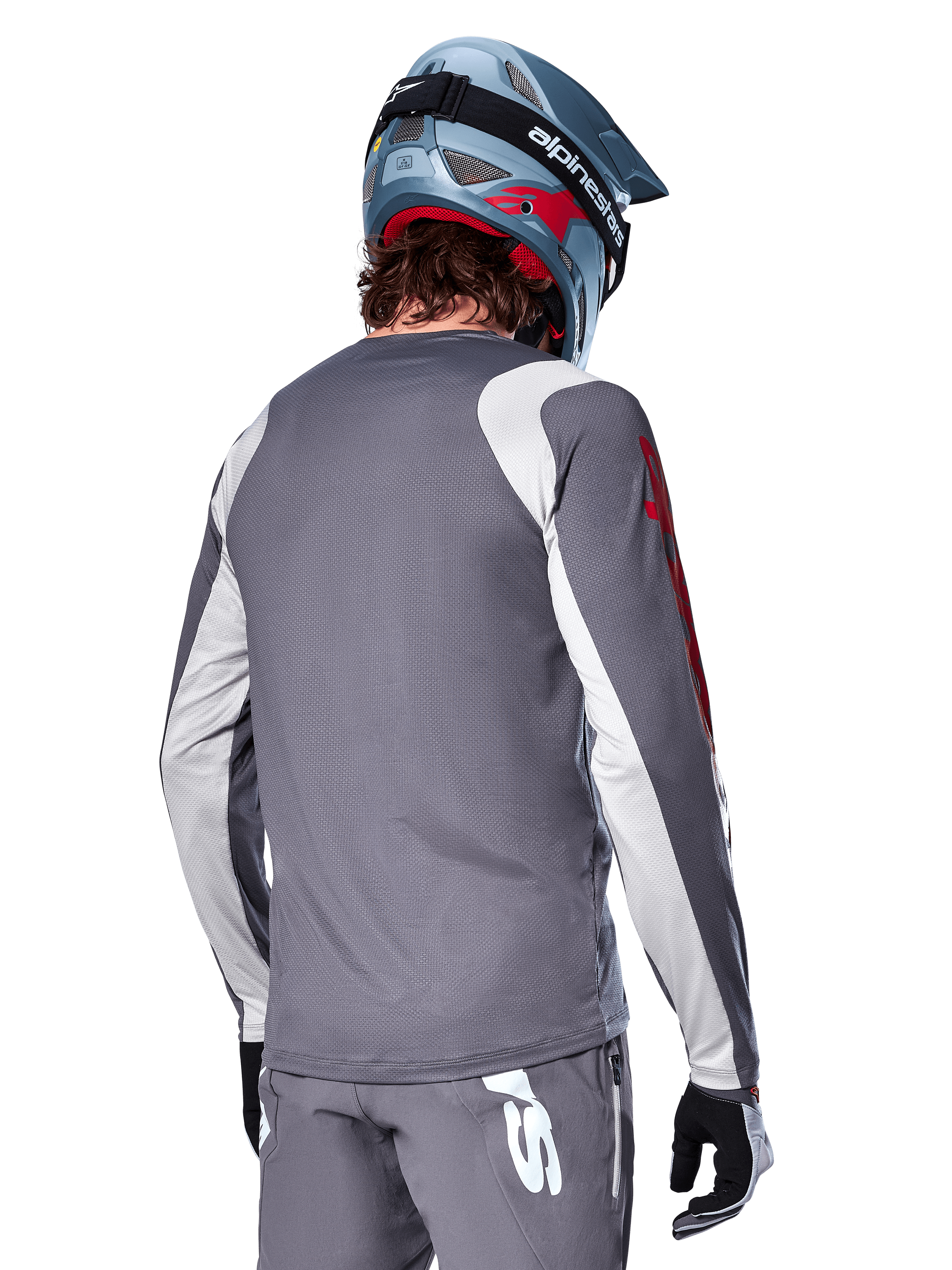 Alpinestars A-Supra Astar Jersey met lange mouwen, donkergrijs met lichtgrijze schouder- en armpanelen, achteraanzicht van een rijder met een blauwe full-face mountainbikehelm en grijze broek, performance-fit MTB-fietskleding