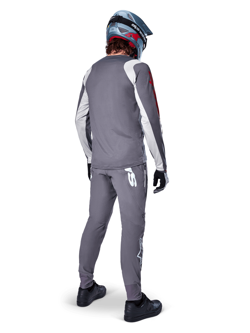 Alpinestars A-Supra Astar Jersey, MTB-jersey met lange mouwen, donkergrijs met witte mouwaccenten en rood logo, achteraanzicht van een rijder met bijpassende grijze broek en blauwe full-face helm, hoogwaardige fietskleding