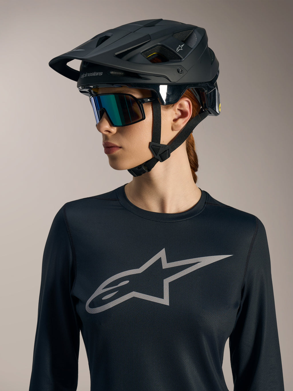 Maillot femme Stella A-Dura Ride noir manches longues, logo Astars gris et casque de VTT noir mat.
