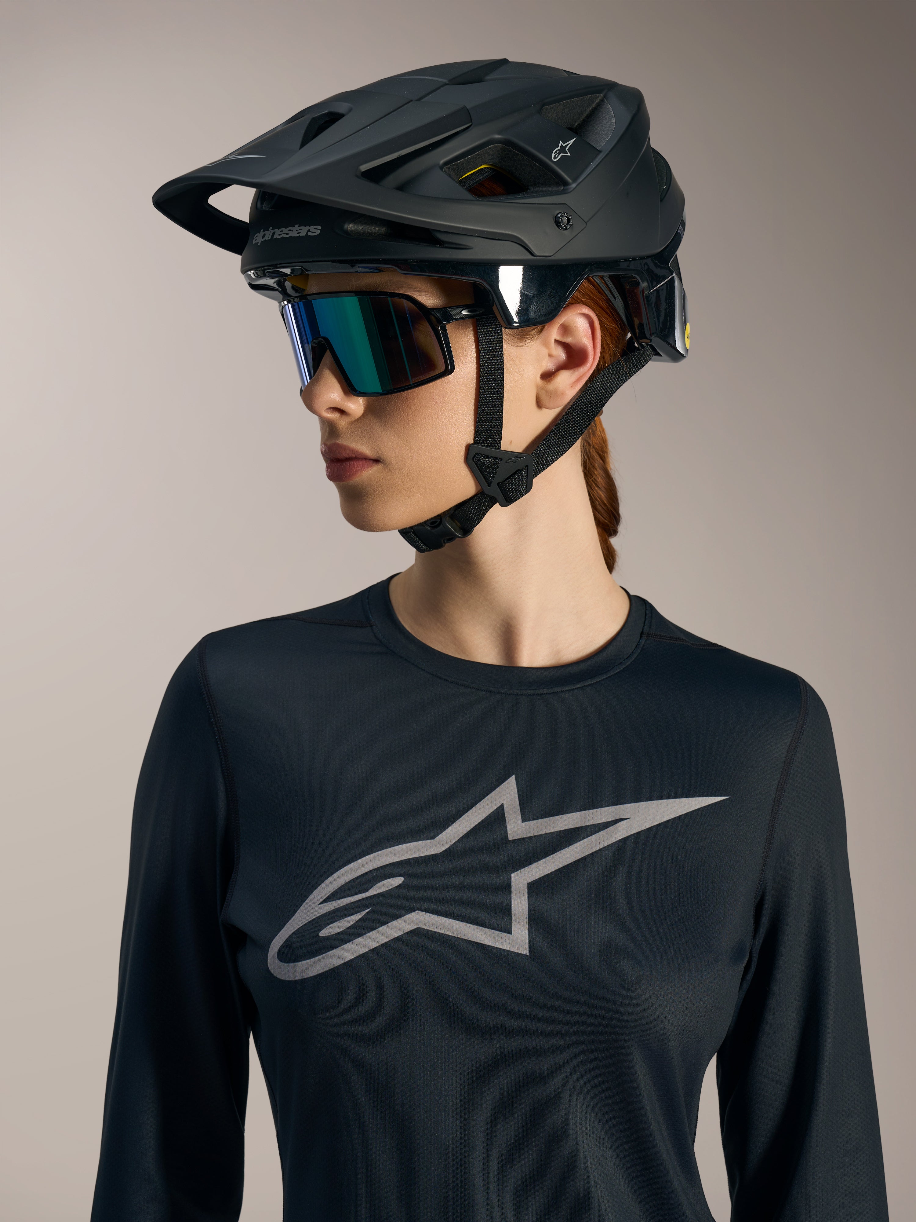 Maillot femme Stella A-Dura Ride noir manches longues, logo Astars gris et casque de VTT noir mat.