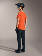 Maillot Alpinestars Stella A-Dura Ride orange pour femme, vue de dos avec pantalon VTT noir et casque.