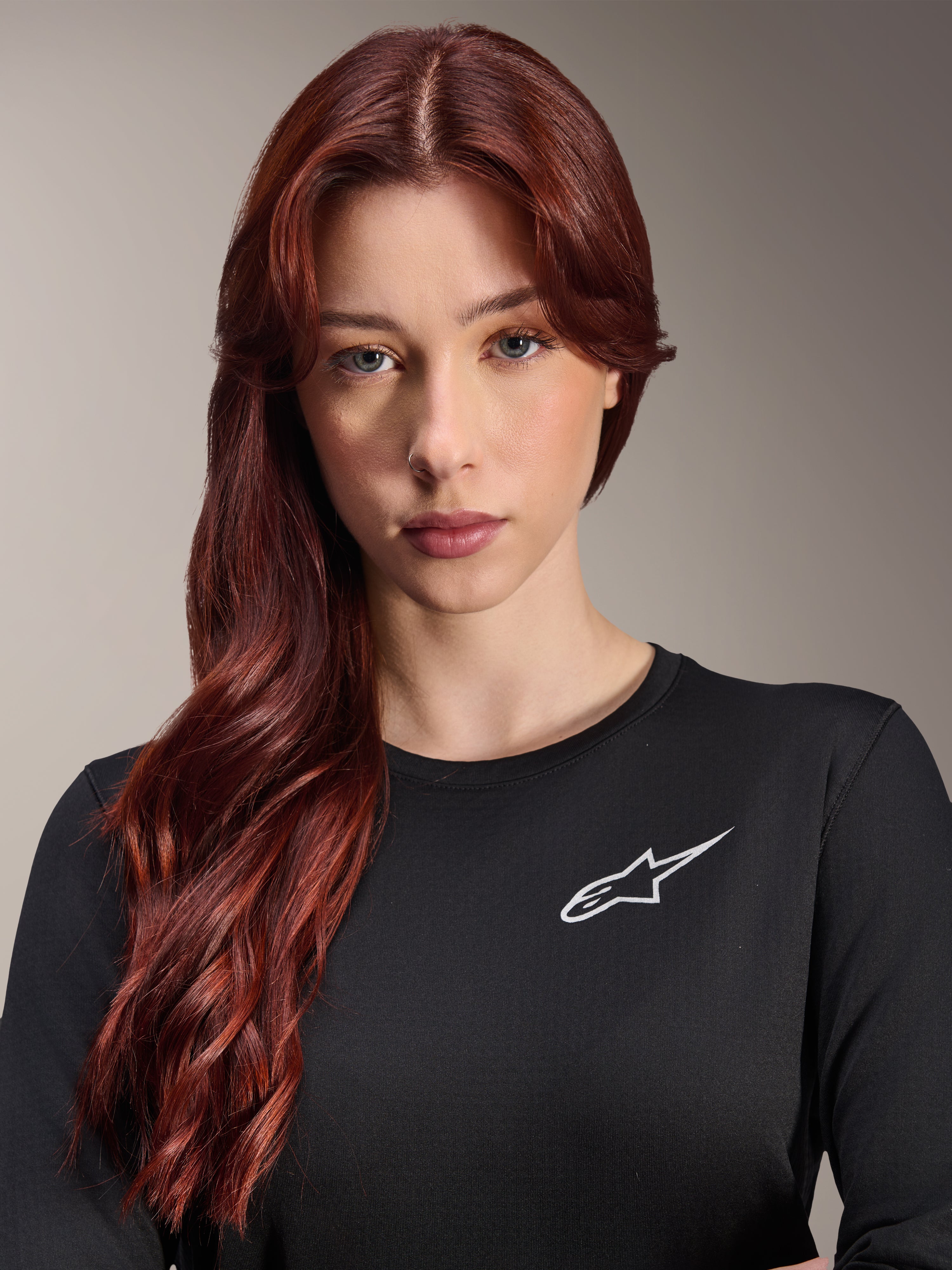 Alpinestars Stella A-Dura Thermal Jersey, MTB-shirt met lange mouwen voor dames, zwart met wit A-star logo op de borst, close-up portret van een vrouw met lang rood haar, fietskleding voor koud weer