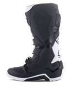 Alpinestars Tech 7 Enduro Drystar® laarzen, enduro motorlaarzen, zwart en wit, zijaanzicht van de mediale zijde met grippanelen met honingraatstructuur, TPU-constructie en witte accenten op de hiel en kuit, professioneel off-road schoeisel