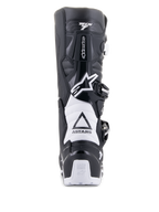 Alpinestars Tech 7 Enduro Drystar-laarzen, zwart en wit, achteraanzicht met TPU-beschermingsstructuur, witte accordeon-flexzones en gespsluitingssysteem, voorzien van Alpinestars-branding op de hiel en het bovenwerk