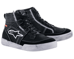 Chaussures Alpinestars Ageless Riding Shoes, chaussures de moto urbaines, noir avec surpiqûres et semelles blanches contrastées, silhouette de baskets montantes avec un grand logo étoile blanc sur le côté, équipement de protection décontracté pour la conduite sur route