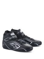 Chaussures Alpinestars Tech-1 T V3 FIA, chaussures de course automobile, noir et argent, construction en cuir de bovin avec logos et marquages Alpinestars argentés, vue latérale inclinée avec sangle auto-agrippante et fermeture à lacets