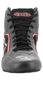 Alpinestars Tech-1 K Start V2 Schuhe, Karting-Schuhe, Asphalt-Schwarz und Orange Fluo, Vorderansicht mit schwarzen Schnürsenkeln, orangefarbenem Alpinestars-Branding auf der Zunge, weißem Stern-Logo auf der Zehenpartie und perforierten Mikrofaser-Einsätzen