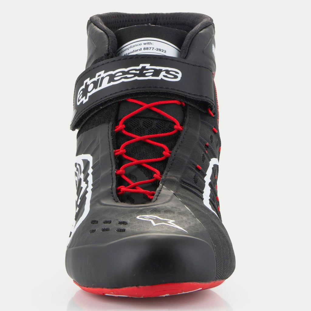 Alpinestars Tech-1 KX V3 schoenen, kartschoenen, zwart, wit en rood, vooraanzicht met rode asymmetrische veters, een zwarte klittenband enkelband met witte branding en een FIA 8877-2022 certificeringslabel op de tong