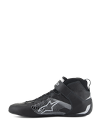 Chaussures Alpinestars Tech-1 Z V3 FIA, chaussures de course automobile, noir et argent, vue de profil, tige en cuir de bovin haut de gamme avec grand logo en étoile stylisée argentée, sangle de cheville à velcro et design montant élégant pour des performances professionnelles en sport automobile.