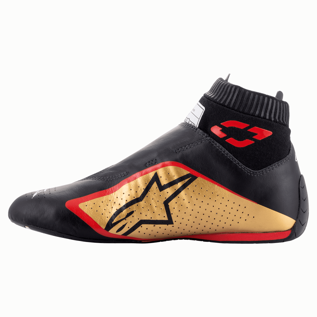Chaussures Alpinestars Supermono V2 FIA, chaussures de course automobile, noir, or et rouge, vue de profil présentant une construction élégante en cuir d'une seule pièce, un panneau latéral doré avec logo étoile noir, des accents rouges et un col élastique côtelé.