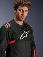 Alpinestars T-Sps Air V2 Jacke, Schwarz mit Red Fluo Akzenten, Textil-Mesh-Motorradjacke, von einem Modell getragen, mit weißem Alpinestars-Logo auf der Brust und den Schultern, atmungsaktive Mesh-Panels, sportlicher urbaner Fahrstil