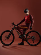 Mountainbiker in Bordeaux A-Dura Elite Jersey 2.0 en bijpassende broek op een Specialized mountainbike in een studio.