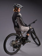 Grijze A-Dura Race trui met lange mouwen op een mountainbiker, met opvallende Alpinestars-logo's en stretchstof.