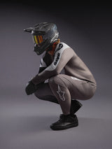 Ensemble VTT A-Supra Elite Alpinestars gris dégradé, maillot et pantalon avec casque intégral et masque de course noirs.