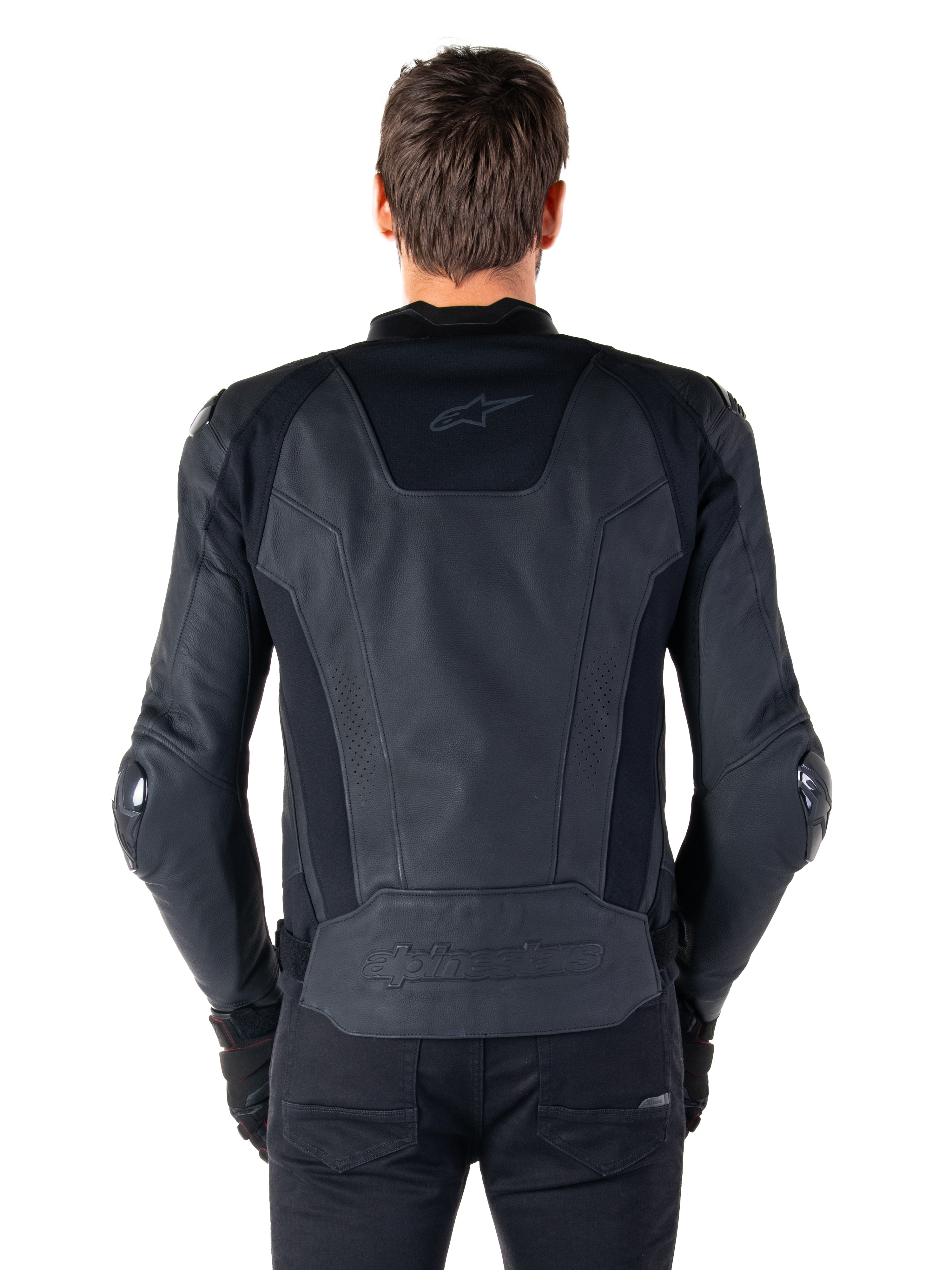 Vue arrière d'un pilote portant la veste en cuir Alpinestars Missile V3 noire, dotée d'une construction en cuir premium avec des panneaux extensibles techniques, logo Alpinestars embossé dans le bas du dos et marquage discret en haut du dos, associée à un pantalon noir pour un look sportif de course coordonné.