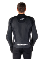 Vue arrière de la veste en cuir Alpinestars Missile V3 en noir et blanc, avec le logo étoile Alpinestars sur le haut du dos, le marquage sur la zone lombaire, des bandes verticales blanches et des sliders de coude externes, veste de sport racing en cuir premium.