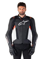 Alpinestars Missile V3 leren jas, zwart, wit en rood fluo, premium racing sportjas van rundleer, wit logo op de borst en Alpinestars-branding op de mouwen, gedragen met zwarte motorhandschoenen en broek