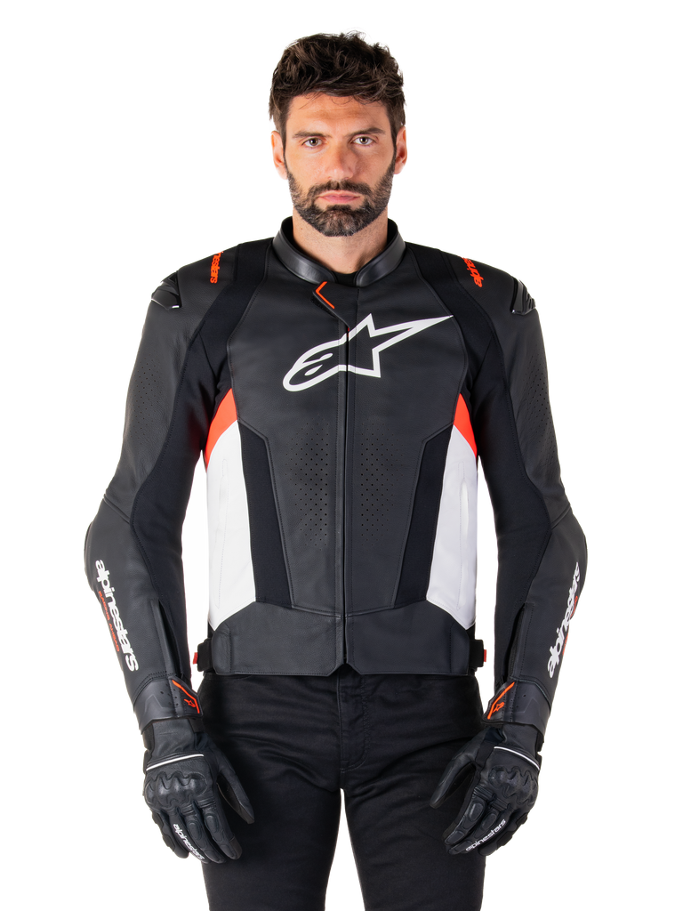 Alpinestars Missile V3 Lederjacke, Schwarz, Weiß und Rot Fluo, Premium-Rennsportjacke aus Rindsleder, mit weißem Brust-Logo und Alpinestars-Branding auf den Ärmeln, getragen mit schwarzen Motorradhandschuhen und einer schwarzen Hose
