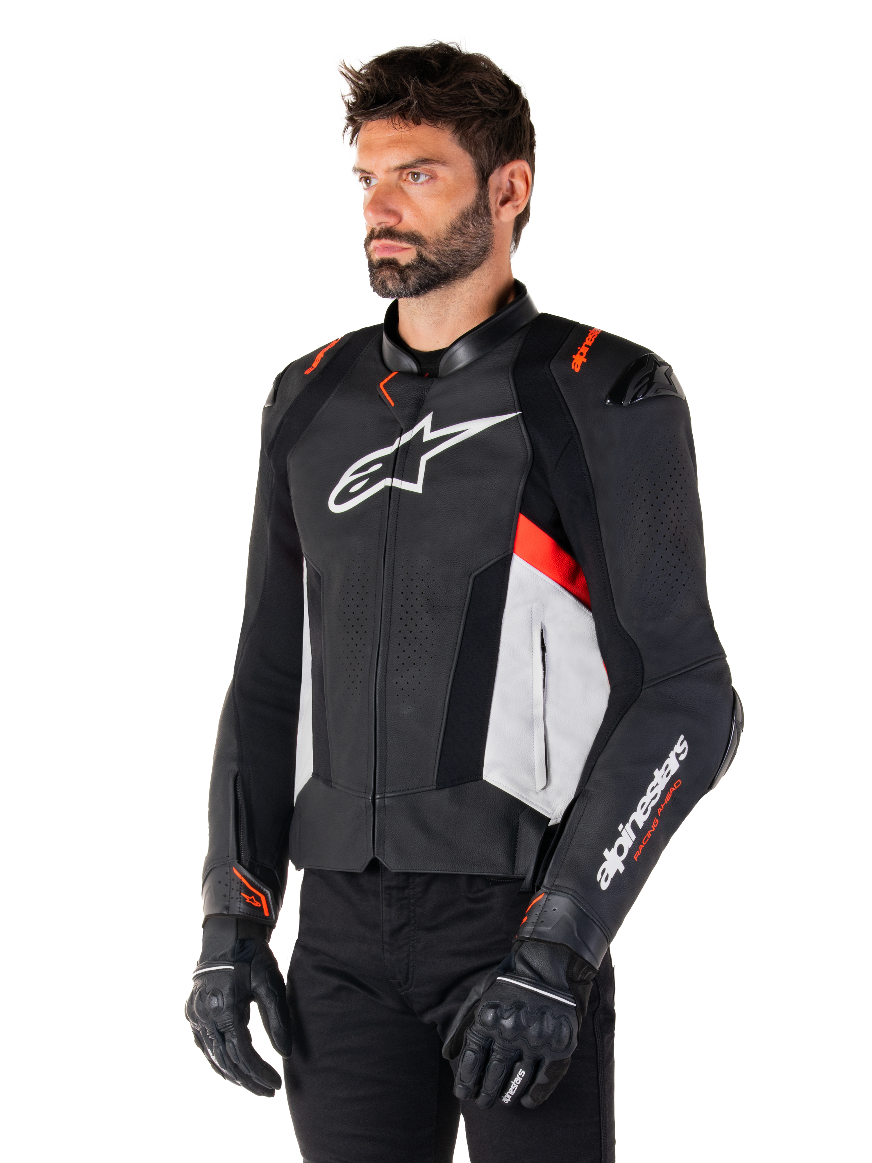 Alpinestars Missile V3 Leren Jas, zwart, wit en rood fluo, racing sport motorjas gedragen door een model met zwarte handschoenen en broek, voorzien van geperforeerde leren panelen en opvallende Alpinestars-branding