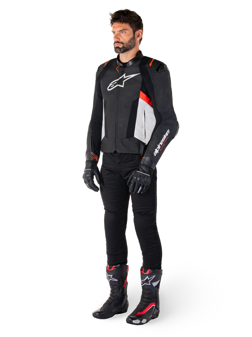 Mannelijk model draagt Alpinestars Missile V3 leren jas in de kleuren zwart, wit en fluo rood, gecombineerd met zwarte motorbroek, handschoenen en laarzen, uitgevoerd in hoogwaardig rundleer met opvallende Alpinestars-branding, professionele racing sport-esthetiek