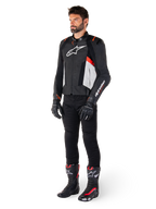 Mannelijk model draagt Alpinestars Missile V3 leren jas in de kleuren zwart, wit en fluo rood, gecombineerd met zwarte motorbroek, handschoenen en laarzen, uitgevoerd in hoogwaardig rundleer met opvallende Alpinestars-branding, professionele racing sport-esthetiek