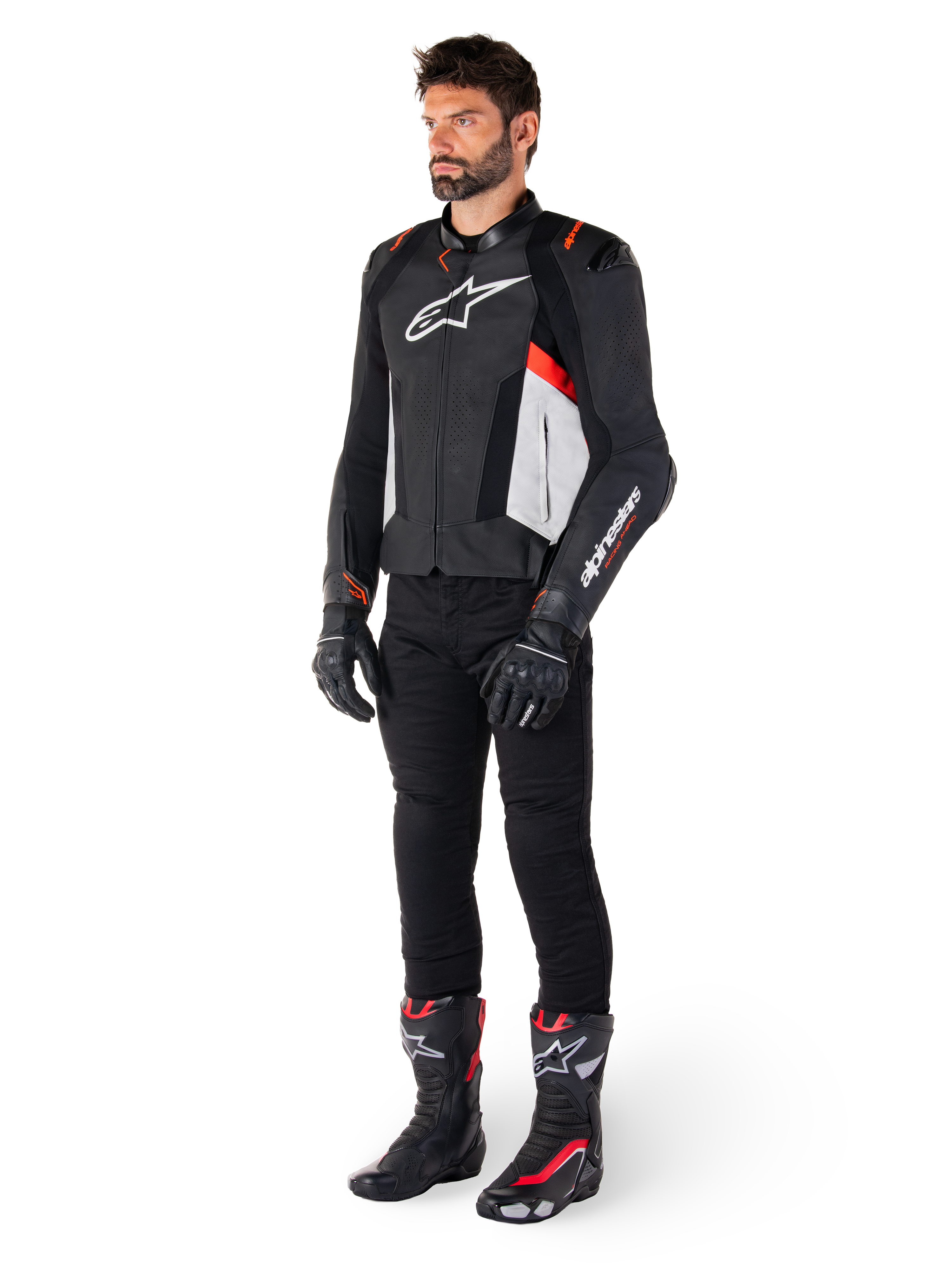 Mannelijk model draagt Alpinestars Missile V3 leren jas in de kleuren zwart, wit en fluo rood, gecombineerd met zwarte motorbroek, handschoenen en laarzen, uitgevoerd in hoogwaardig rundleer met opvallende Alpinestars-branding, professionele racing sport-esthetiek