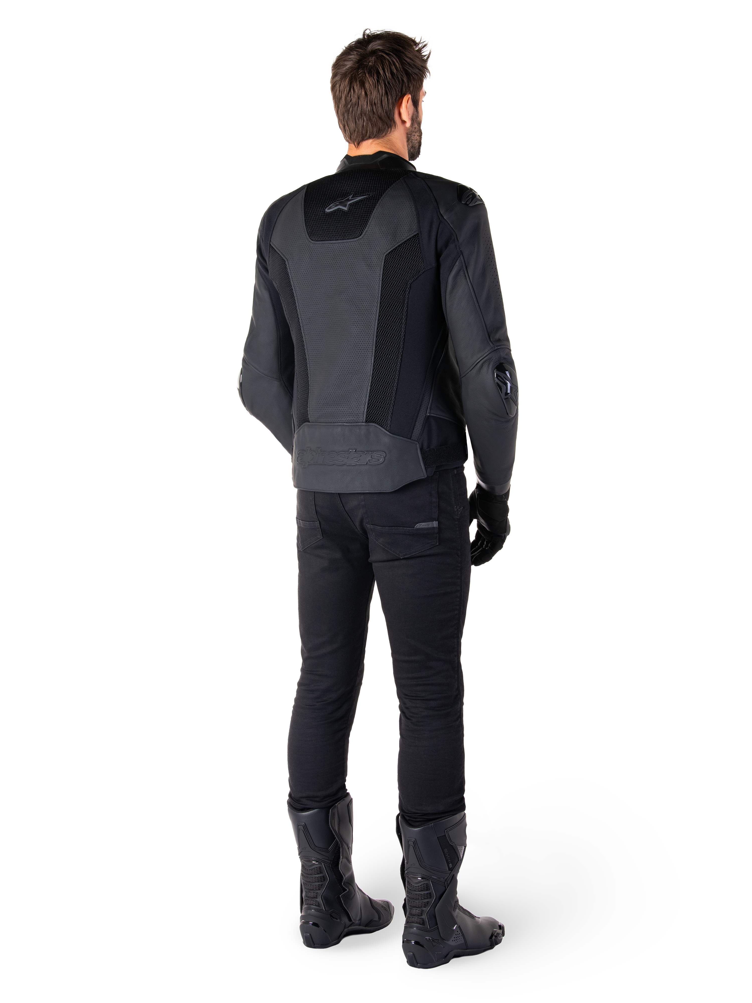 Rückansicht eines Mannes in der Alpinestars Missile V3 Airflow Lederjacke in Schwarz, mit großflächigen perforierten Einsätzen zur Belüftung, kombiniert mit schwarzer Motorradhose und Stiefeln, eine stromlinienförmige Rennsport-Ästhetik präsentierend.