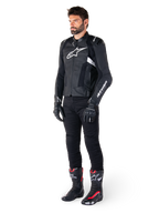 Alpinestars Missile V3 Airflow Lederjacke, Schwarz und Weiß, getragen von einem männlichen Model mit schwarzer Motorradhose, schwarzen Handschuhen und Rennstiefeln mit roten und weißen Akzenten, mit perforiertem Leder und weißem Logo-Branding, Performance-Motorrad-Rennausrüstung