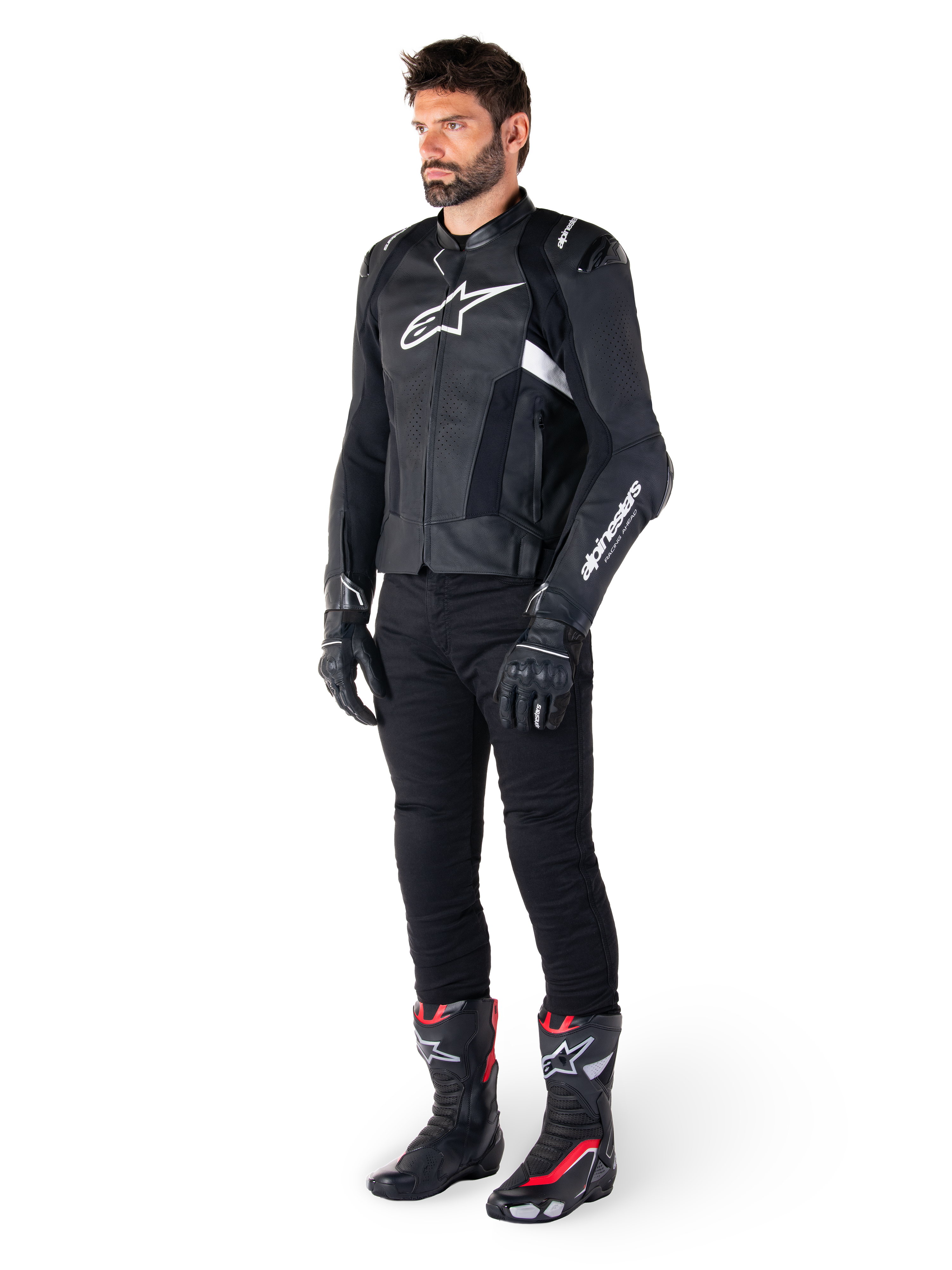 Alpinestars Missile V3 Airflow Lederjacke, Schwarz und Weiß, getragen von einem männlichen Model mit schwarzer Motorradhose, schwarzen Handschuhen und Rennstiefeln mit roten und weißen Akzenten, mit perforiertem Leder und weißem Logo-Branding, Performance-Motorrad-Rennausrüstung