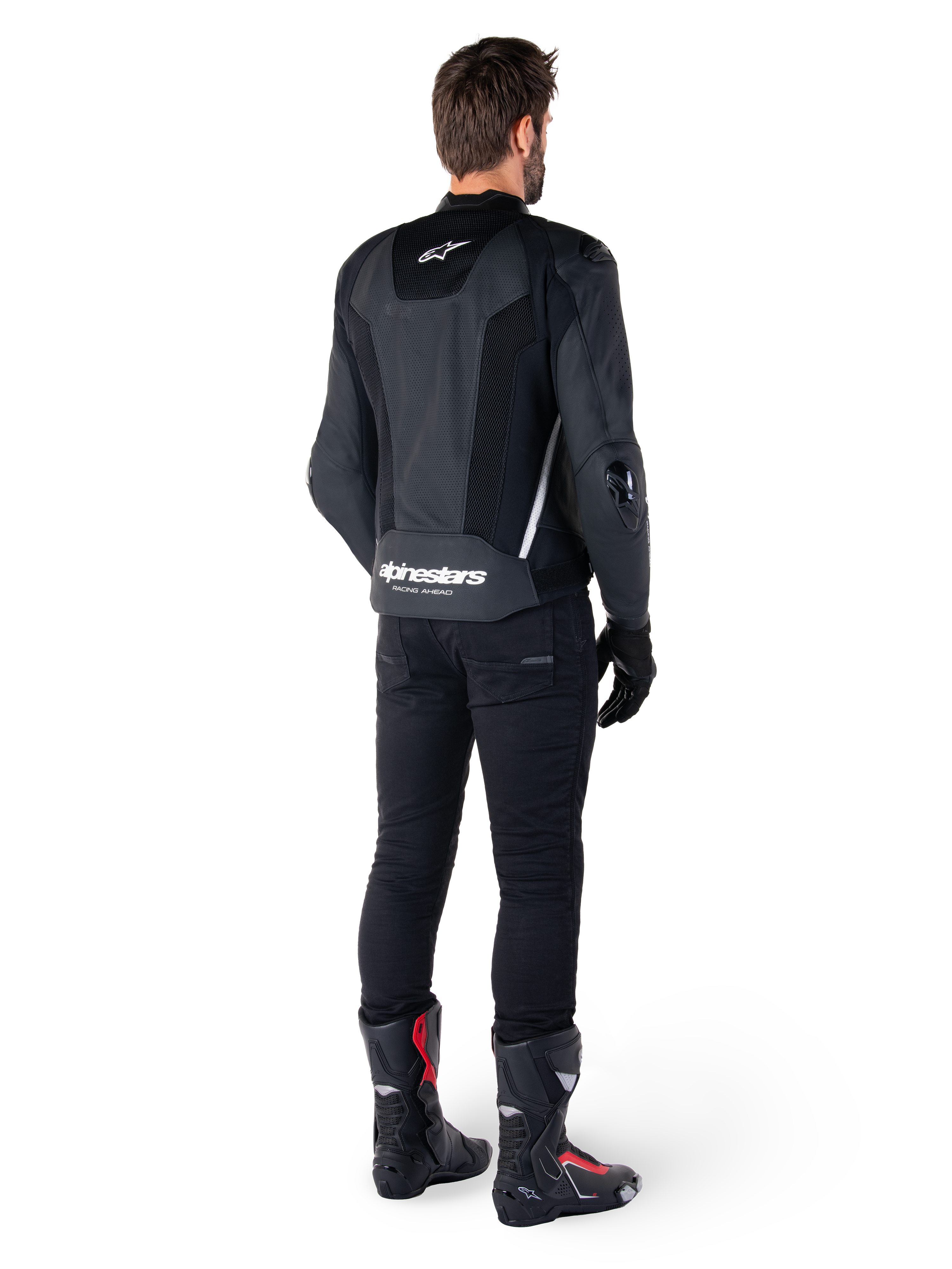Alpinestars Missile V3 Airflow Lederjacke, Schwarz/Weiß, Rückansicht getragen mit schwarzer technischer Hose und Rennstiefeln, mit perforierten Leder-Rückeneinsätzen und markantem Alpinestars-Branding am unteren Rücken.