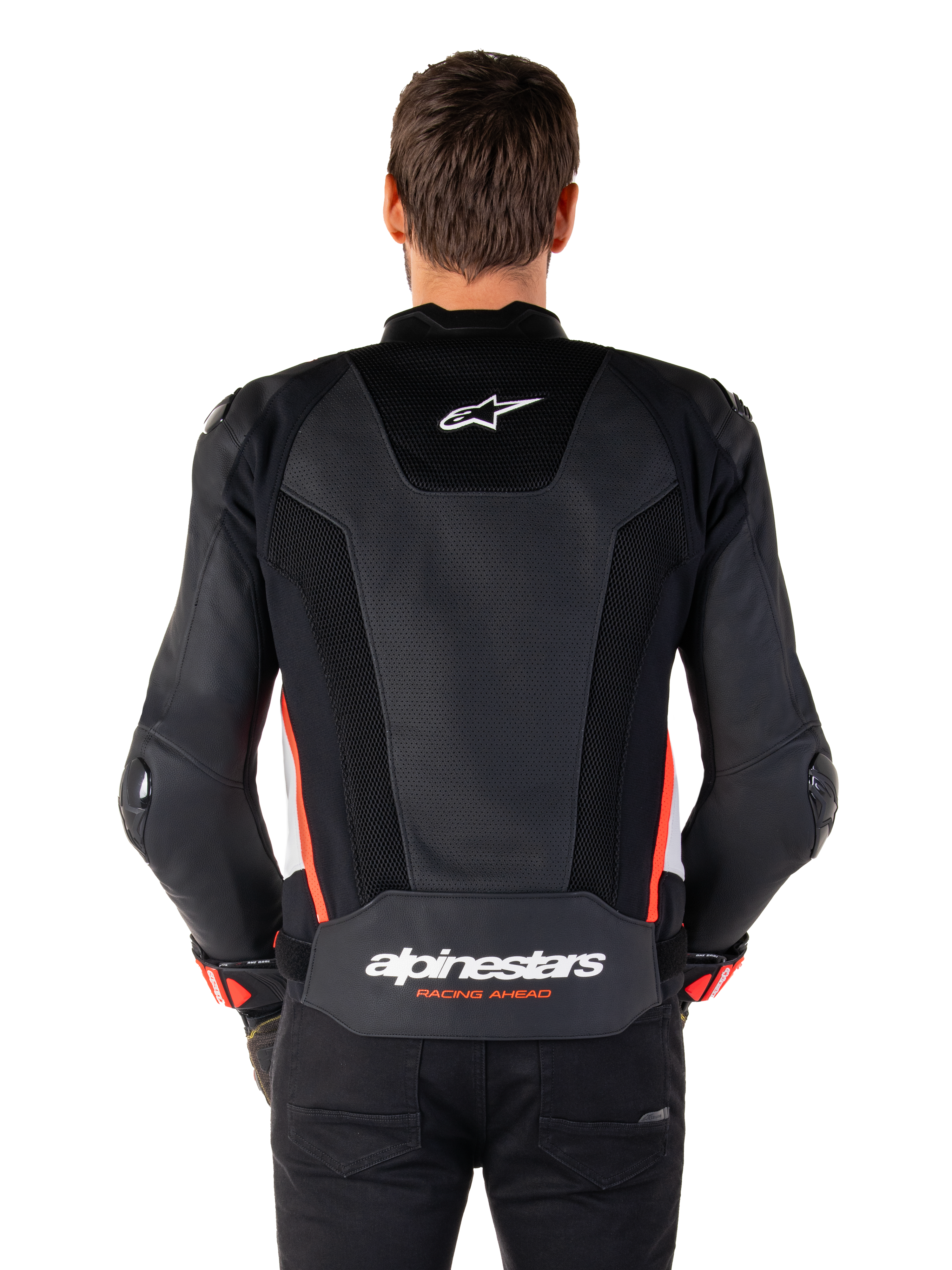 Rückansicht einer Person, die die Alpinestars Missile V3 Airflow Lederjacke in Schwarz Weiß Rot Fluo trägt, mit großflächigen perforierten Lederbahnen zur Belüftung, einem kleinen Alpinestars-Logo auf dem oberen Rücken und dem markanten „alpinestars RACING AHEAD“-Branding am unteren Taillenbereich.