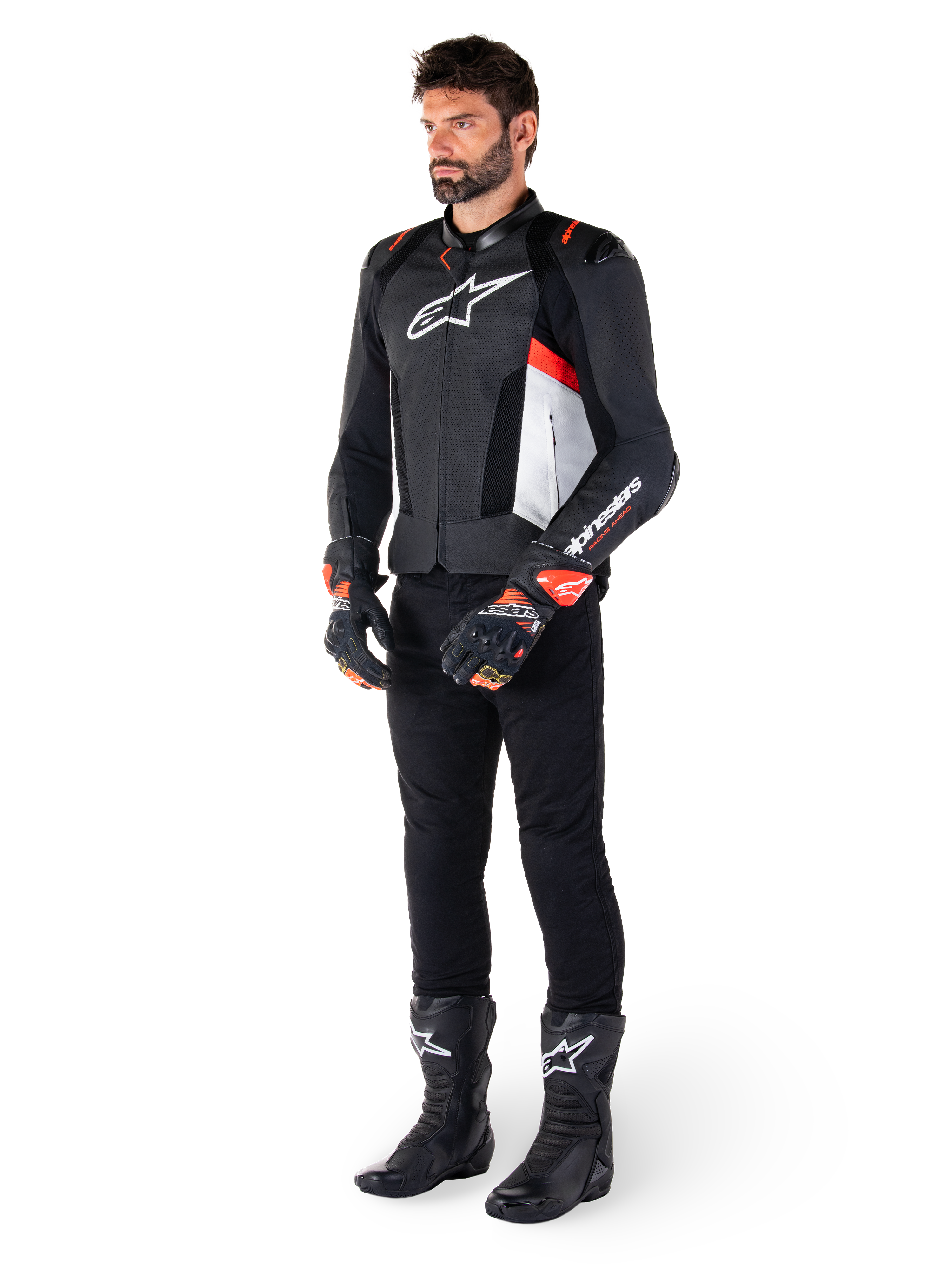 Alpinestars Missile V3 Airflow Lederjacke, Schwarz Weiß Rot Fluo, getragen von einem männlichen Model mit schwarzer Hose, schwarzen Rennhandschuhen und schwarzen Stiefeln, mit perforiertem Leder für Belüftung, weißem Brustlogo und fluoreszierenden roten Akzenten, entwickelt für erstklassige Renn- und Sport-Performance.