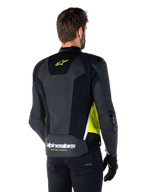 Alpinestars Missile V3 Airflow Lederjacke, Rückansicht an einem männlichen Modell, Schwarz mit neongelben und weißen Akzenten, großflächige perforierte Leder- und Mesh-Einsätze am Rücken, gelbes Stern-Logo und weißer „RACING AHEAD“-Schriftzug, kombiniert mit schwarzen Handschuhen und einer schwarzen Hose.