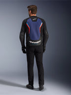 Alpinestars GP Force V2 Lederjacke, Sport-Motorradjacke, Schwarz Blau Rot Fluo, Rückansicht an einem Model, mit großem blauem Rückenteil, roten und hellblauen Akzenten sowie weißem Alpinestars-Branding am unteren Rücken, kombiniert mit schwarzer Motorradhose und Handschuhen.