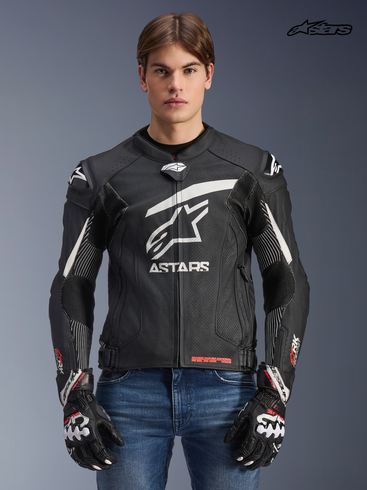Alpinestars GP Plus R V4 Rideknit leren jas, heren motorracingjas in zwart en wit, vooraanzicht op model met bijpassende handschoenen en jeans, race-afgeleide bescherming en technische stretchpanelen