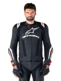 Alpinestars Missile V3 Ignition Lederjacke, Schwarz mit weißen und roten Akzenten, getragen von einem männlichen Model mit passenden Rennhandschuhen und -hose, aus der MotoGP abgeleitete Sport-Motorradjacke mit markantem Branding