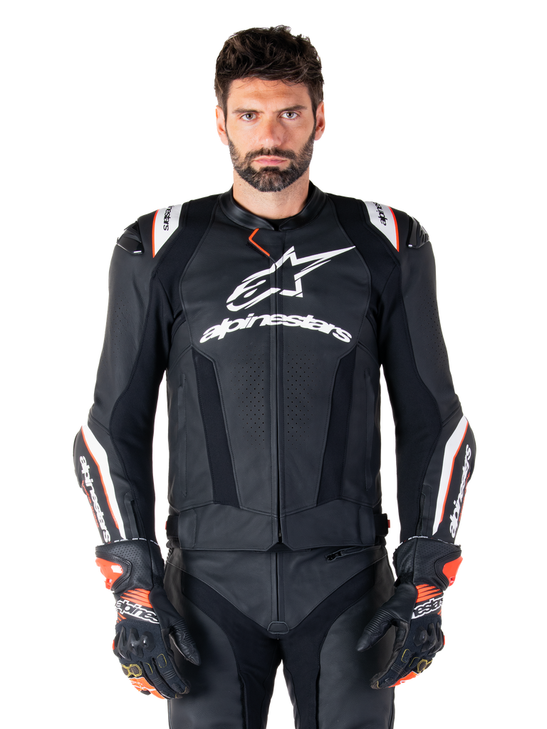 Alpinestars Missile V3 Ignition Lederjacke, Schwarz mit weißen und roten Akzenten, getragen von einem männlichen Model mit passenden Rennhandschuhen und -hose, aus der MotoGP abgeleitete Sport-Motorradjacke mit markantem Branding