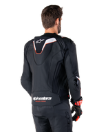 Alpinestars Missile V3 Ignition Lederjacke, Rückansicht, Schwarz mit weißen und roten Akzenten, mit schmalem Sport-Aero-Höcker und Alpinestars-Branding, getragen mit passender Lederhose und Rennhandschuhen