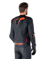 Alpinestars Missile V3 Ignition Leather Jacket, Men's Racing Sport Jacket, Black with Red Fluo accents, back view featuring the slim aerodynamic sport hump and Alpinestars branding on the lower back, worn with black leather pants and racing gloves, sleek professional motorsport design