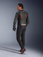 Männliches Model in der Rückansicht trägt die Alpinestars GP Force V2 Air Lederjacke in Schwarz-Rot-Fluo, mit umfassenden Perforationen am Rücken und markantem weißem Branding, kombiniert mit schwarzen Motorradjeans, Handschuhen und schwarz-roten Motorradstiefeln in einer Studioumgebung.