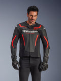 Alpinestars GP Force V2 Air Lederjacke, Motorrad-Rennjacke, Schwarz und Rot Fluo, hochwertige Lederkonstruktion mit großflächiger Perforation für optimale Belüftung, getragen von einem Model mit schwarzen Handschuhen und Hosen, mit markantem Branding und 'Racing Ahead'-Schriftzug auf der Brust